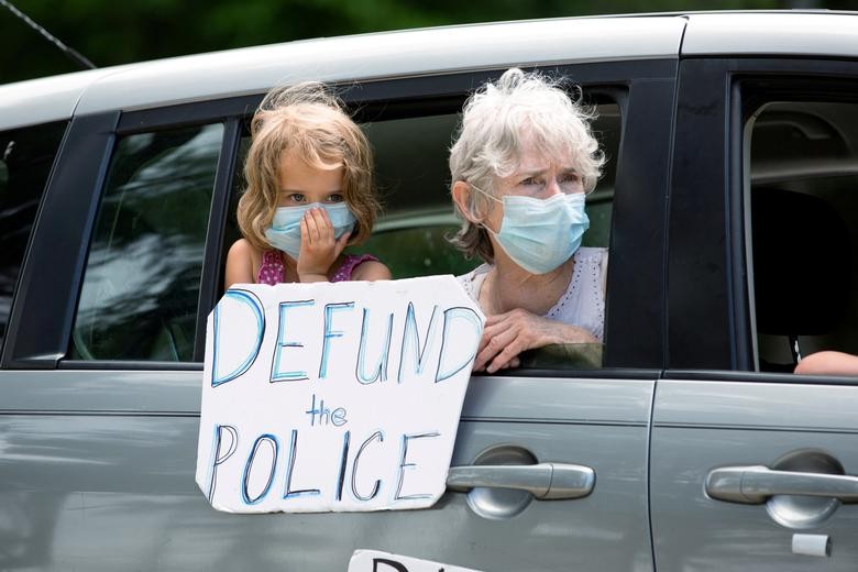 A grandmother and granddaughter hold a sign and look on as protesters march against the Confederate monument carved into granite at Stone Mountain Park in Stone Mountain, Georgia, June 16, 2020. REUTERS/Dustin Chambers